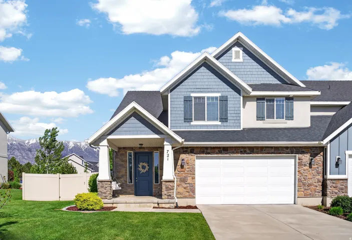 Two-story residence featuring a stone and siding facade, an attached two-car garage, and a covered entry porch