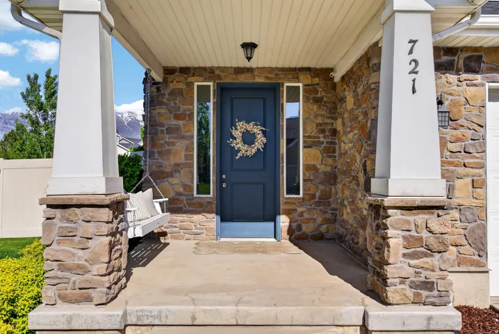 Stone facade entry featuring a dark blue door with side windows, and a covered porch with white columns