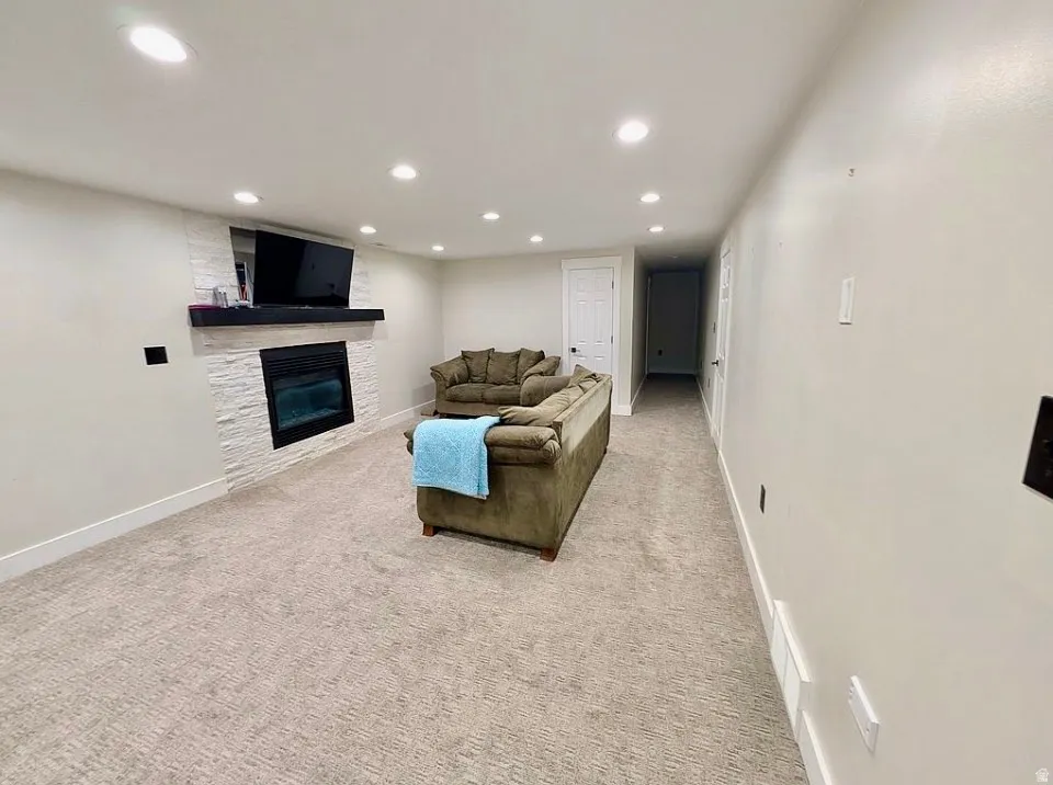 Media room featuring recessed lighting, plush carpeting, an electric fireplace with a stacked stone surround, and a dark wood mantel