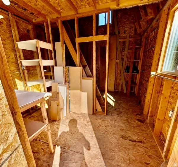Wood-finish flooring throughout an unfinished interior with exposed wood framing
