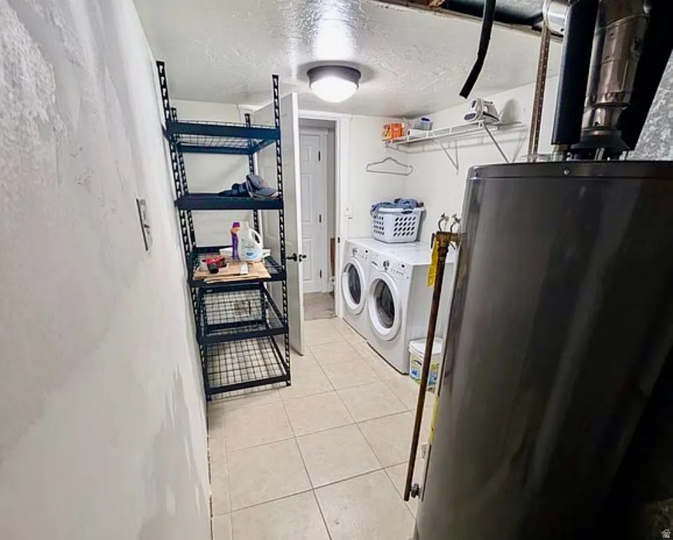 Laundry area with tile flooring, wall-mounted shelving, and overhead lighting