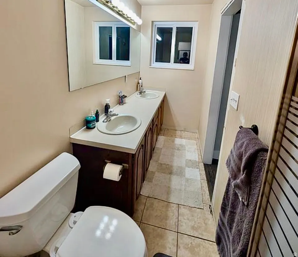 Dual vanity with integrated sinks, a white countertop, and wood-finish cabinetry