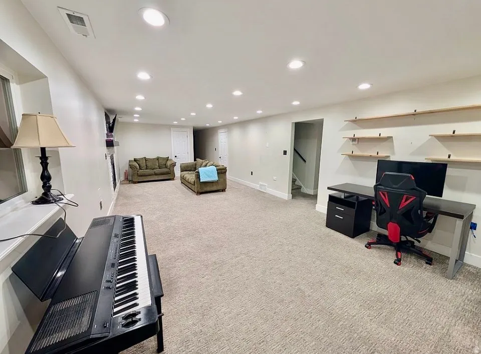 Spacious room featuring neutral carpeting, recessed lighting, and white walls