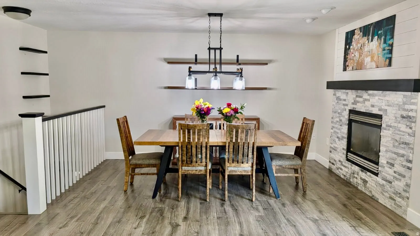 Open-concept dining area featuring wood-finish flooring and a stone-clad fireplace