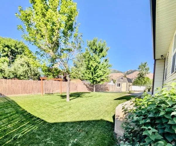 Expansive lawn featuring mature trees and a privacy fence