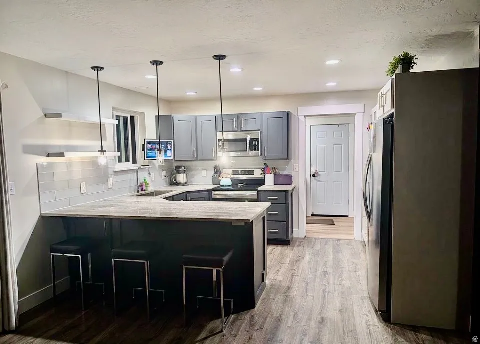 U-shaped kitchen featuring grey cabinetry, stainless steel appliances, and a light-toned countertop