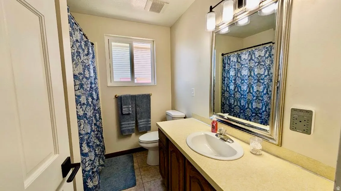 Bathroom featuring a single vanity with a light-toned countertop, an integrated sink, and an expansive framed mirror