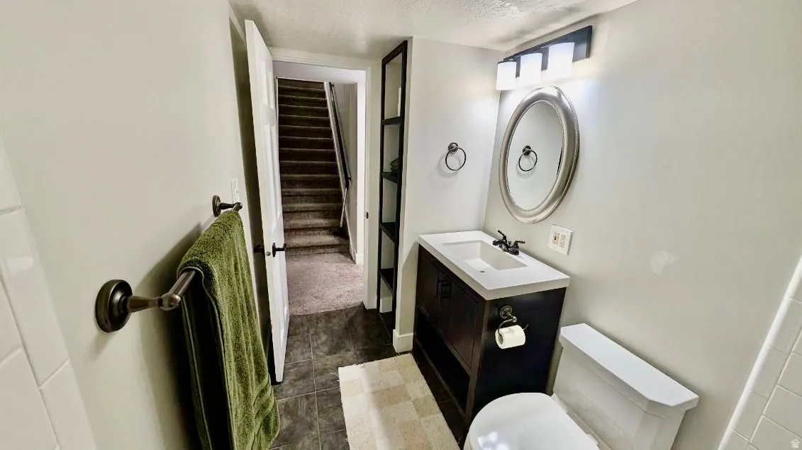 Bathroom featuring a dark wood-finish vanity with a white countertop and rectangular sink, an oval mirror, and a three-light fixture