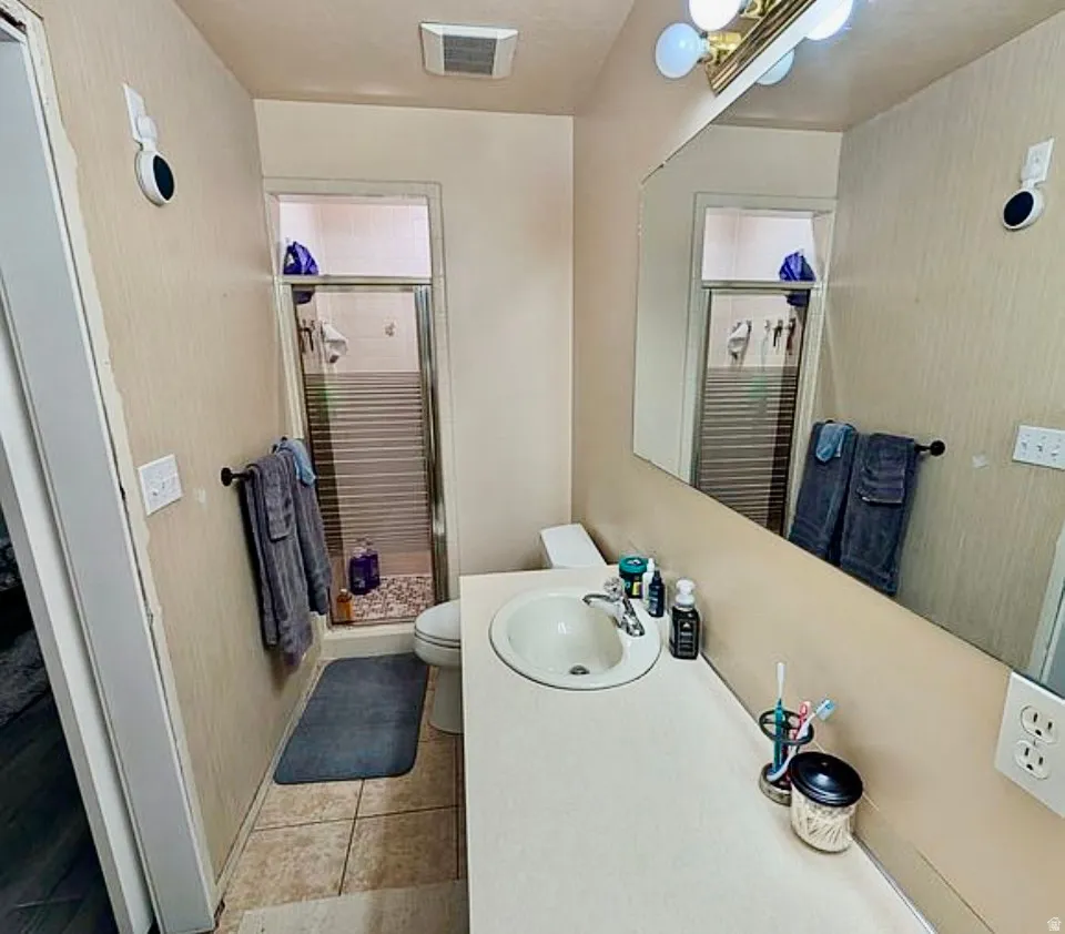 Bathroom featuring a single vanity with a laminate countertop, an integrated sink, and an expansive wall mirror