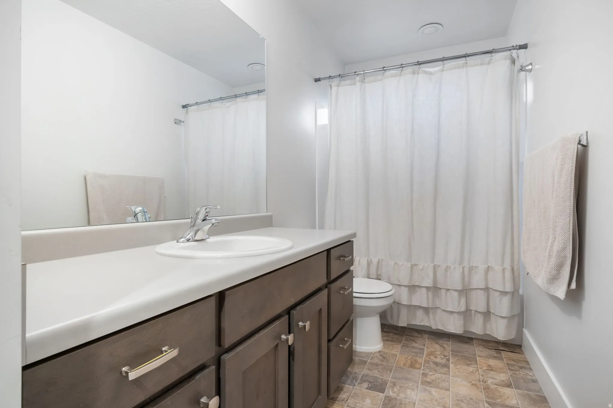 Bathroom featuring a vanity with a light-colored countertop, an integrated sink, and dark wood-finish cabinetry