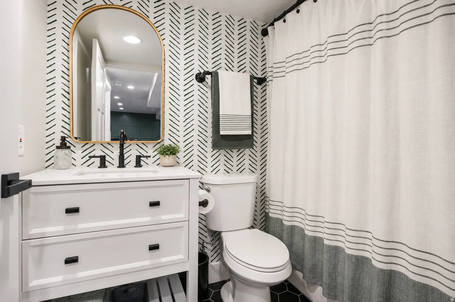 Bathroom featuring a white vanity with a rectangular basin and black hardware, set against patterned wallpaper