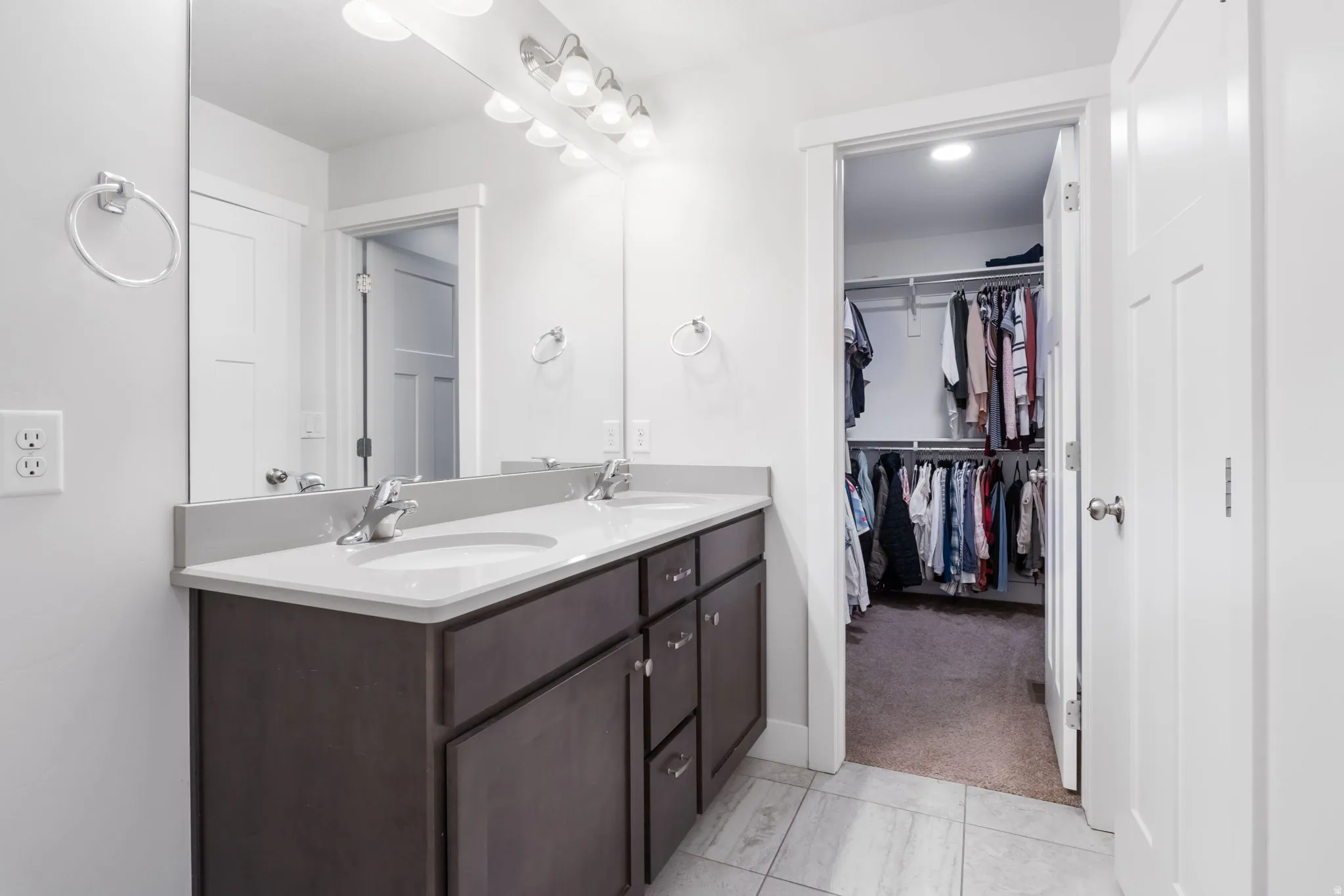 Bathroom vanity featuring a double sink, light-colored countertop, and dark wood-finish cabinetry