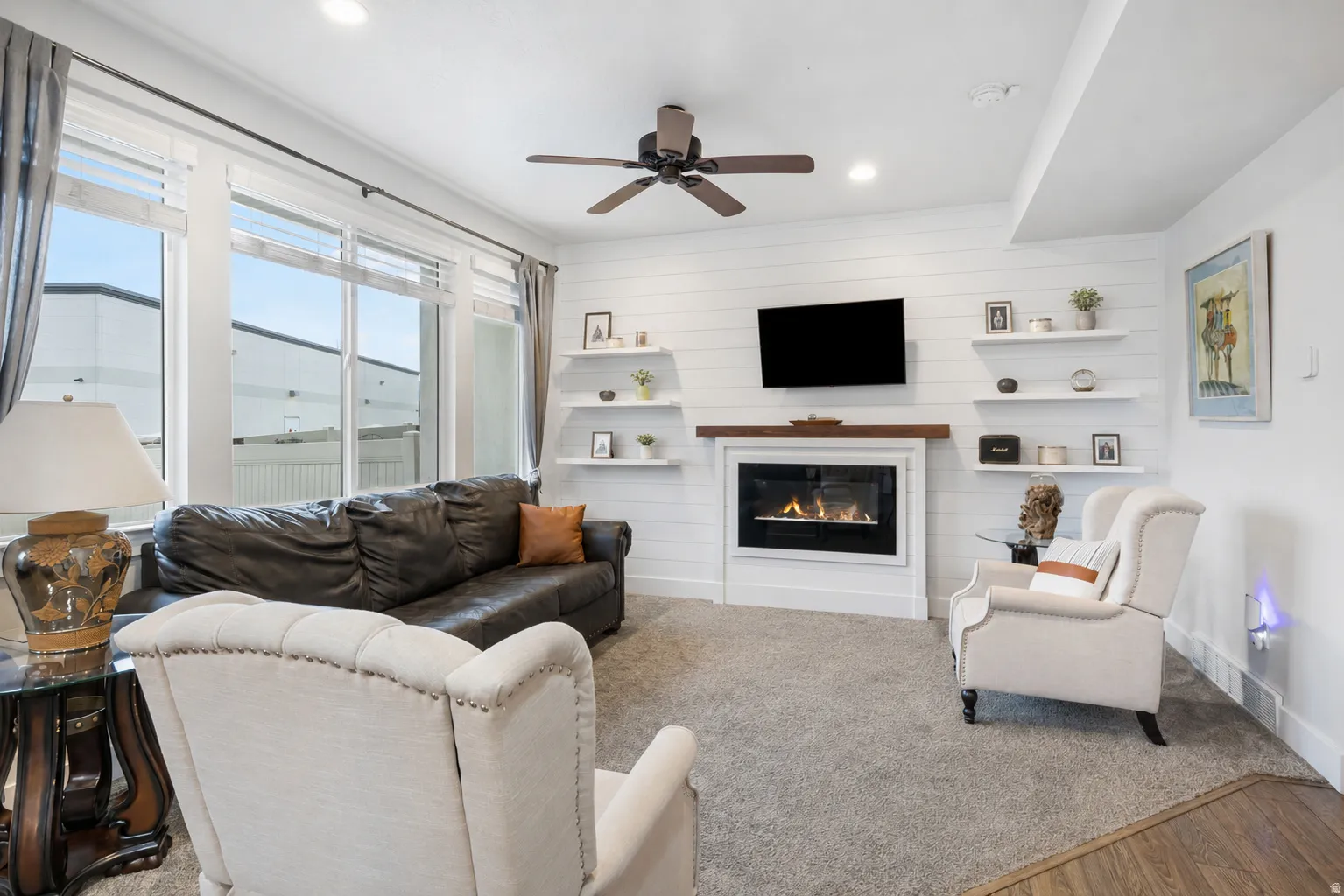 Living area featuring a shiplap accent wall with a built-in fireplace, a wood mantel, and floating shelves