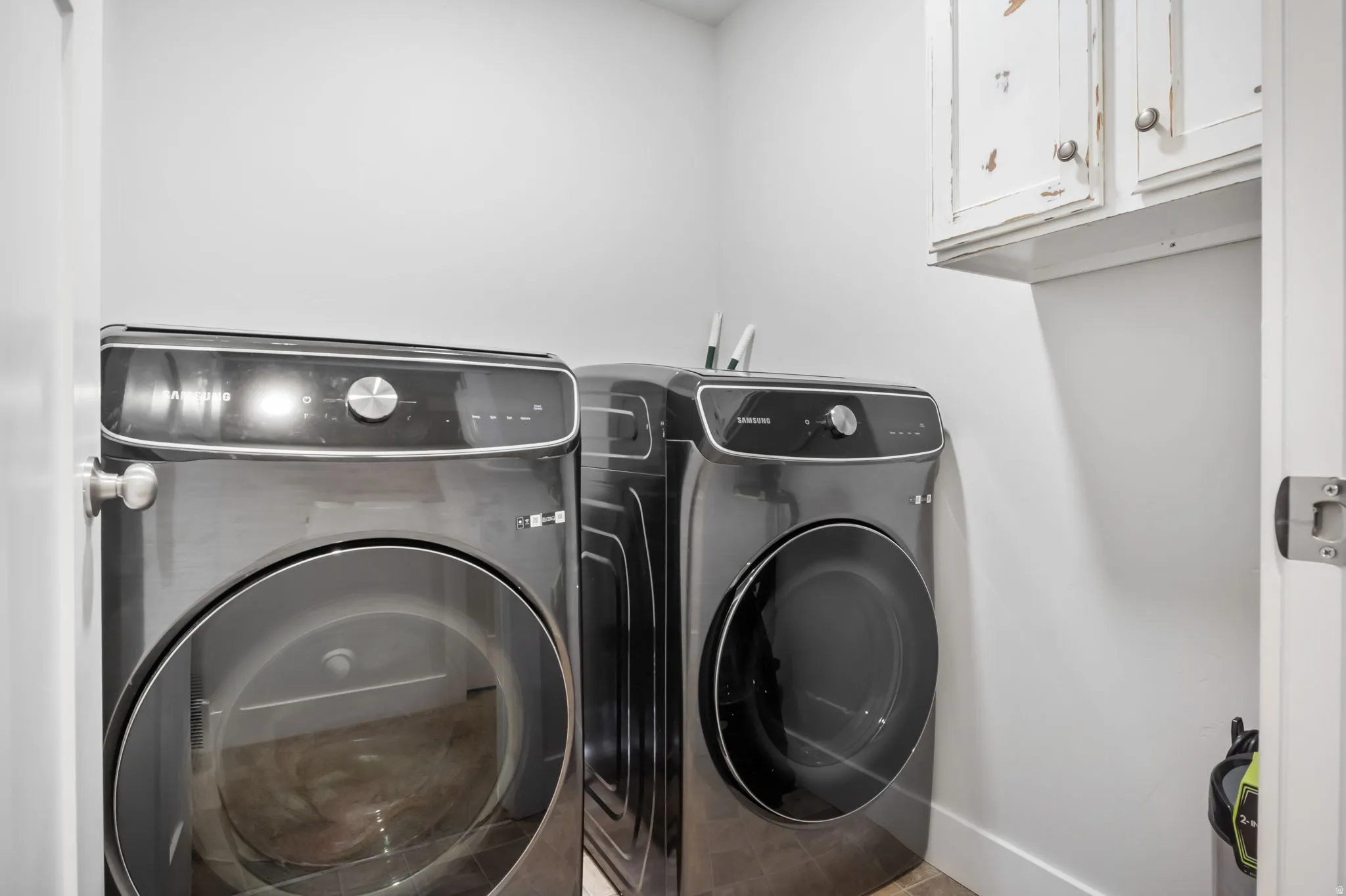 Dedicated laundry area featuring white walls, baseboards, and upper cabinetry