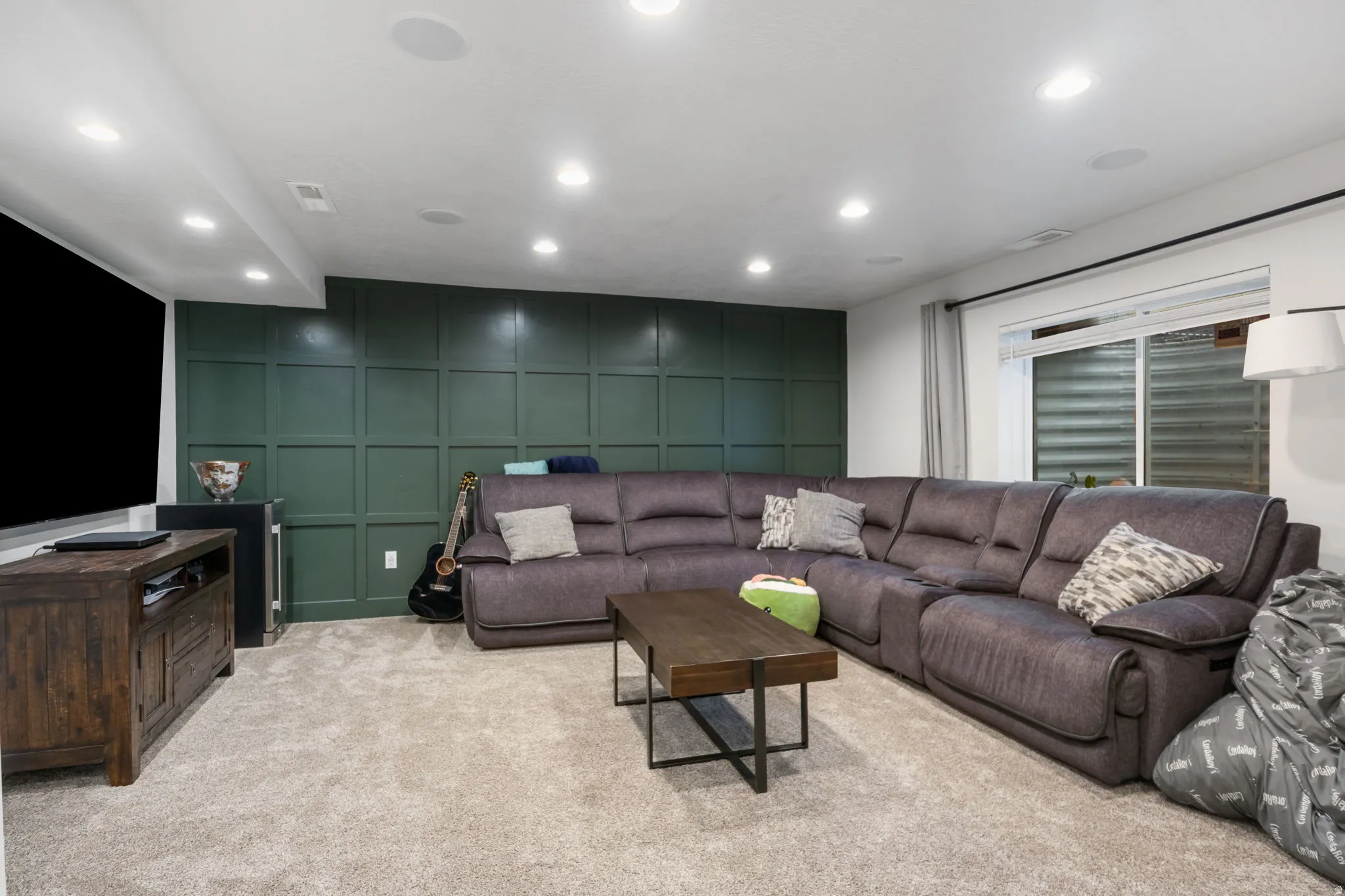 Carpeted recreation room featuring a paneled accent wall, recessed lighting, and a built-in media cabinet