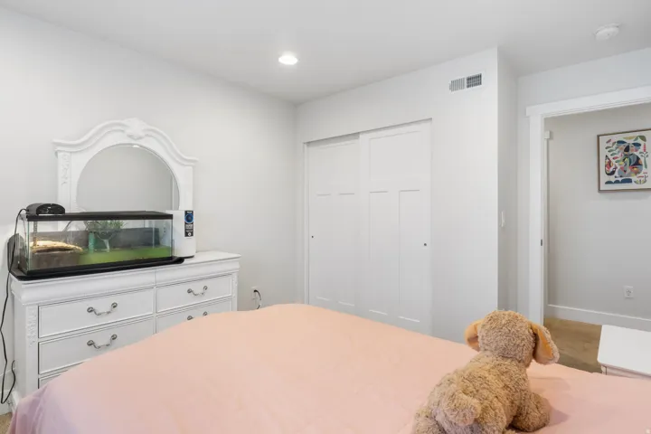 Bedroom featuring white walls, recessed lighting, and a built-in sliding closet with paneled doors