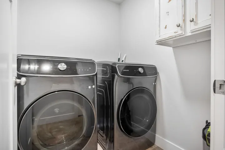 Dedicated laundry area featuring white walls, baseboards, and upper cabinetry
