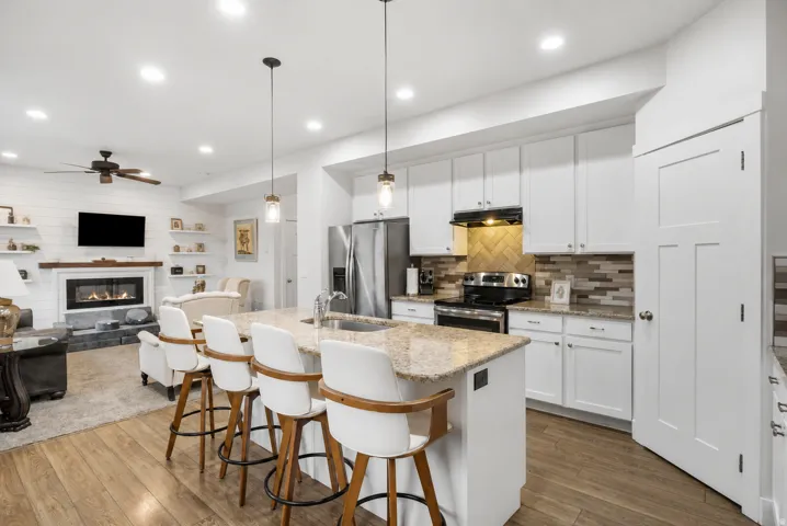Open-concept kitchen and living area featuring wood-finish flooring, recessed lighting, and a kitchen island with seating