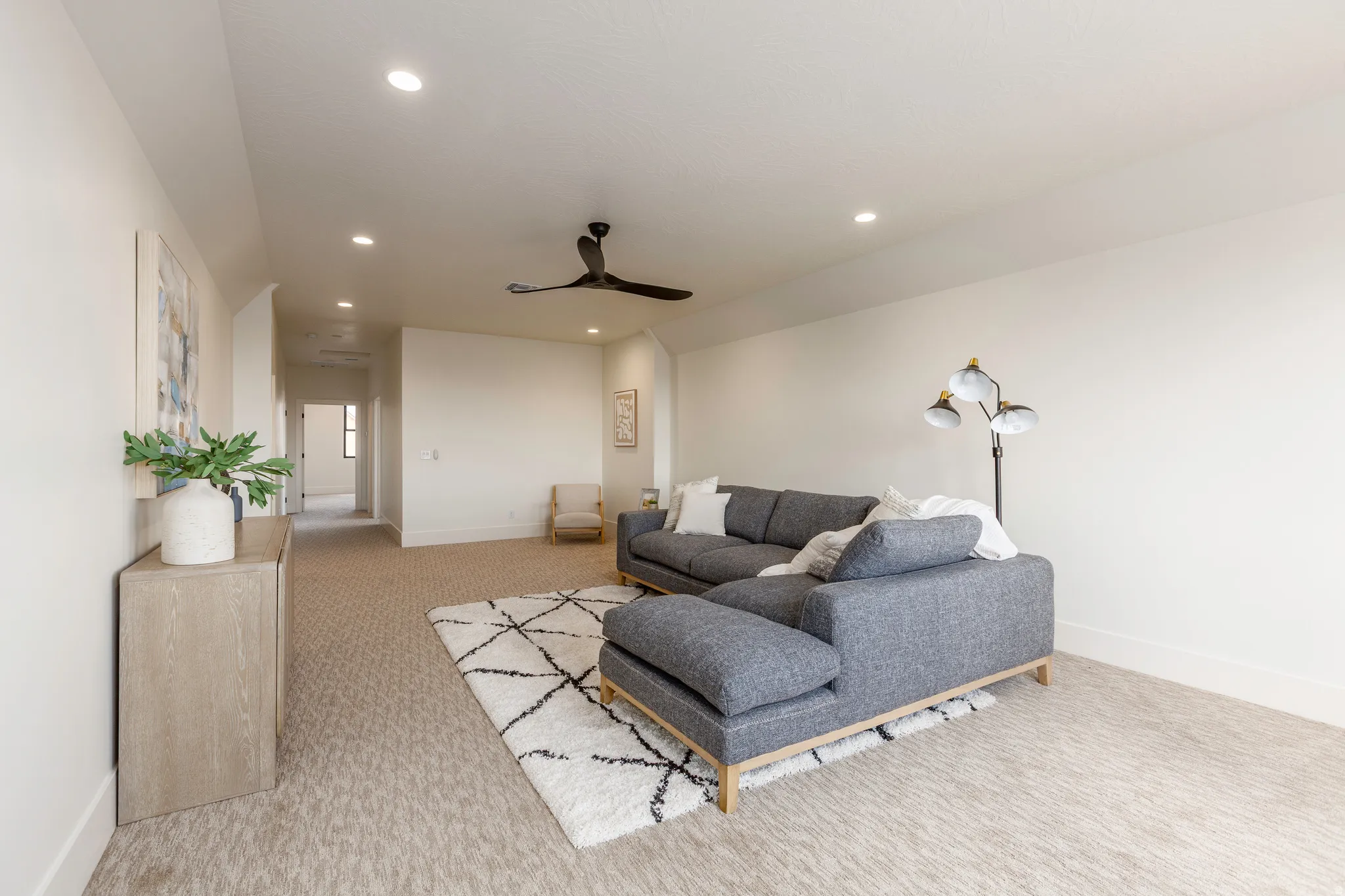 Spacious living area featuring neutral carpeting, recessed lighting, and a contemporary ceiling fan