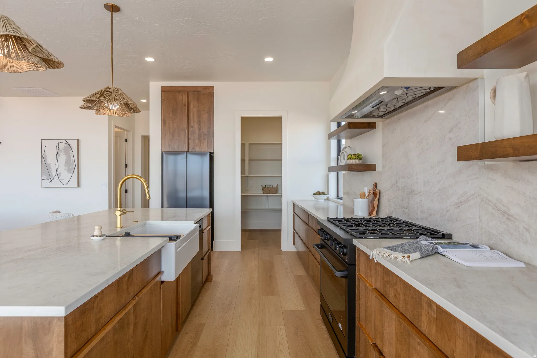 Gourmet kitchen featuring a large central island with an integrated farmhouse sink and gold-finish faucet