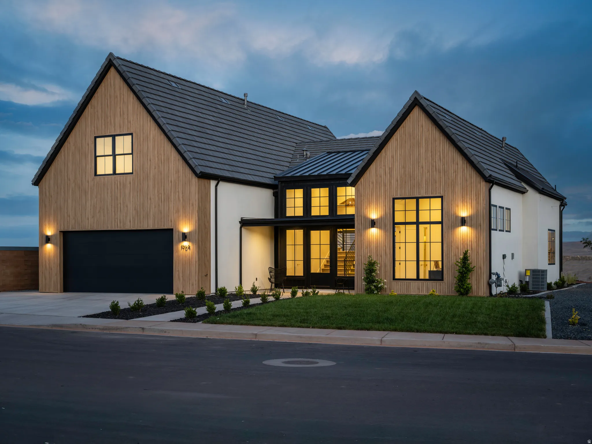 Modern farmhouse-style exterior featuring a black roof, light-toned vertical wood-look siding, white stucco accents, and black-framed windows