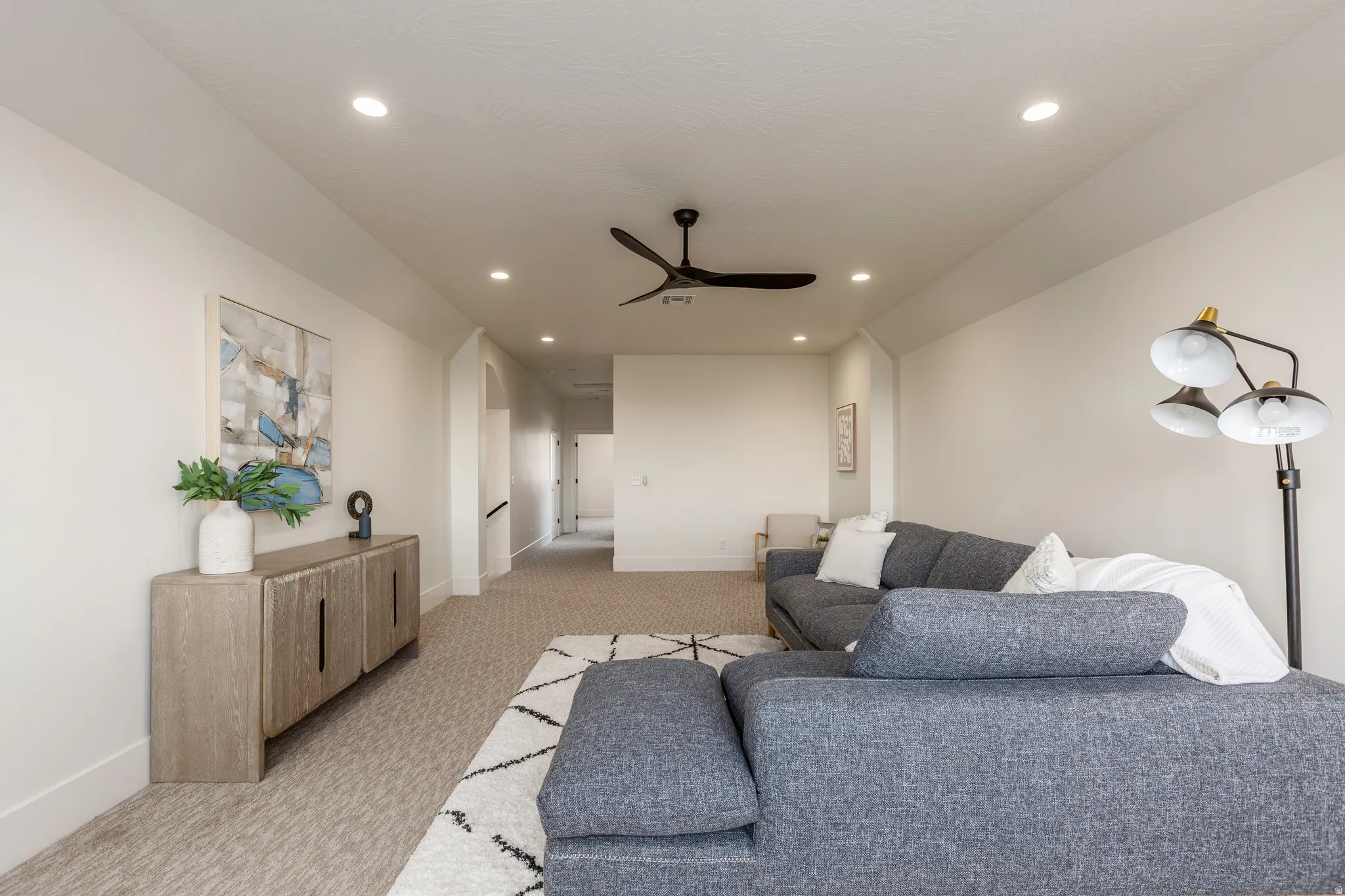 Spacious room featuring neutral carpeting, recessed lighting, and a contemporary ceiling fan