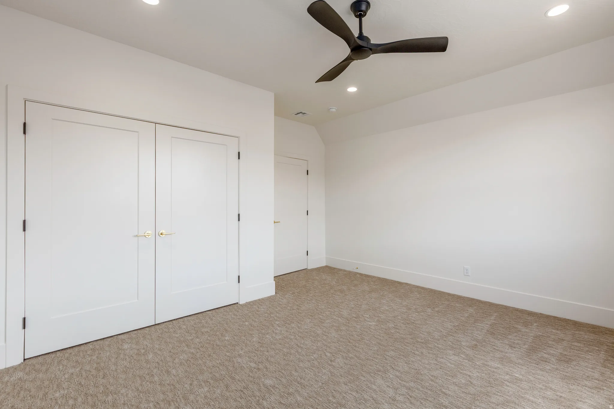 Spacious room featuring neutral carpet, white walls, recessed lighting, and a modern ceiling fan