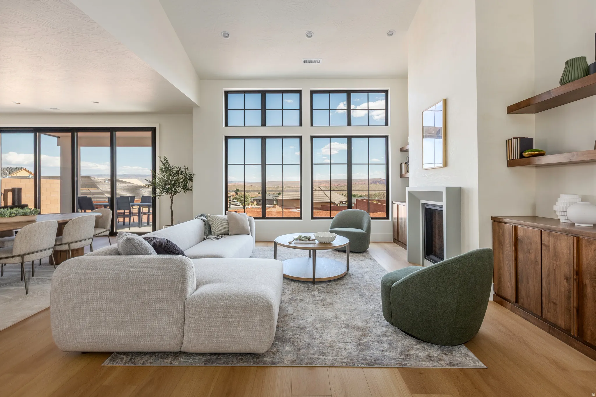 Spacious living area featuring high ceilings, wood-finish flooring, and a modern fireplace