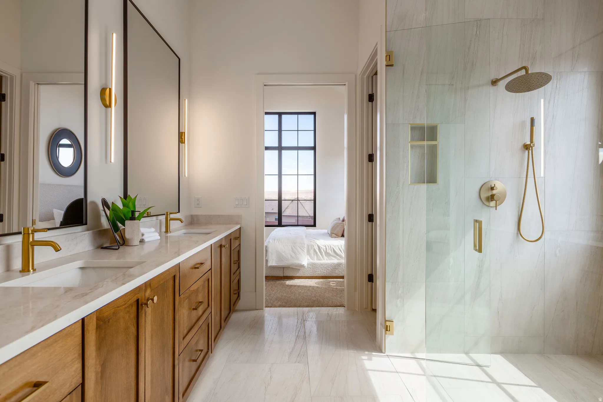 Double vanity featuring wood cabinetry, stone countertops, and gold-finish fixtures