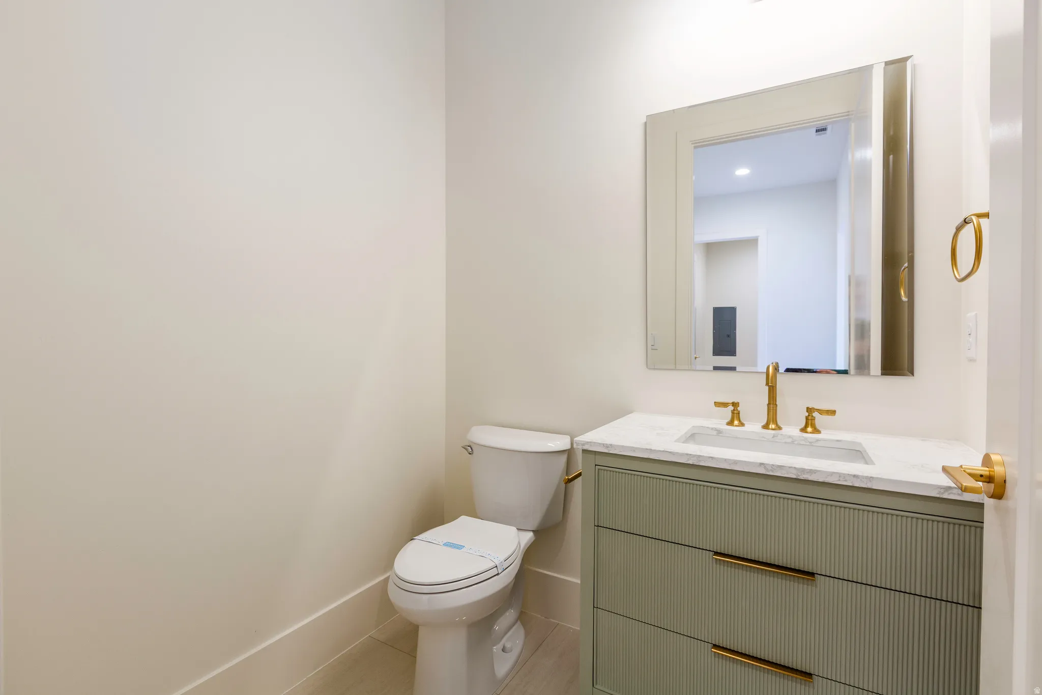 Contemporary vanity with a fluted front and integrated sink, featuring a polished brass faucet and coordinating hardware