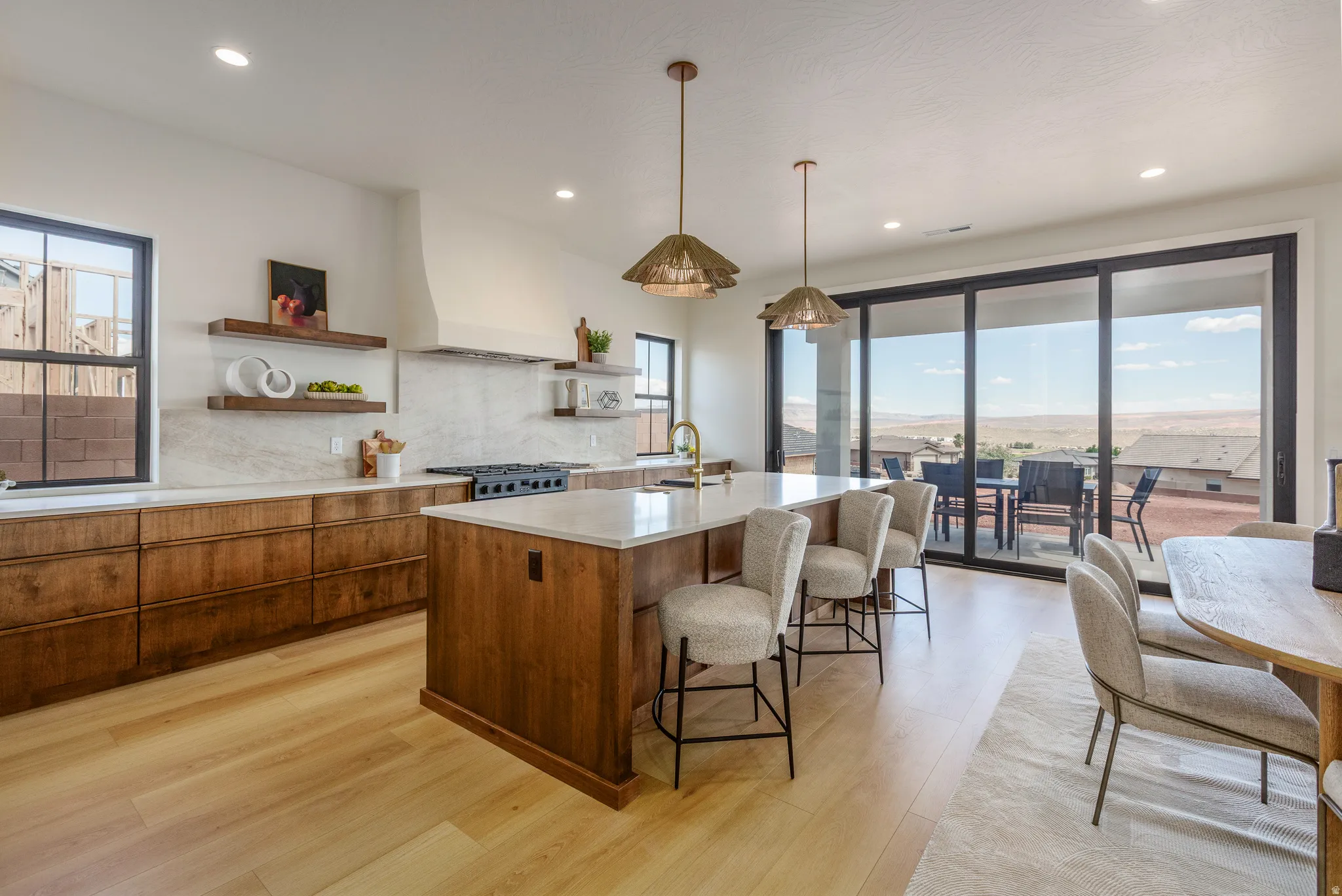 Open-concept kitchen featuring wood-finish cabinetry, a large center island with counter seating, light-toned countertops, and light wood-finish flooring