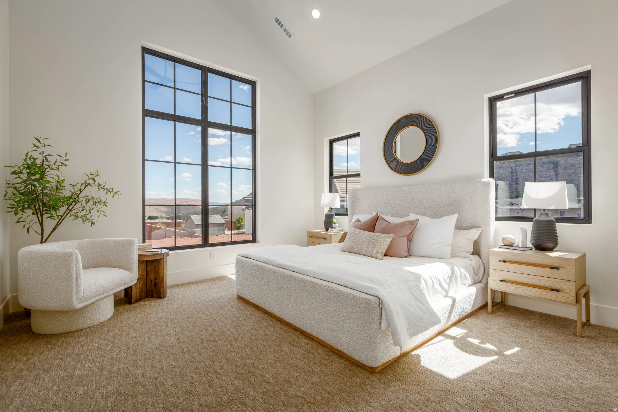 Vaulted ceiling bedroom featuring a large picture window with black framing, two additional windows with black framing, and neutral-toned carpeting
