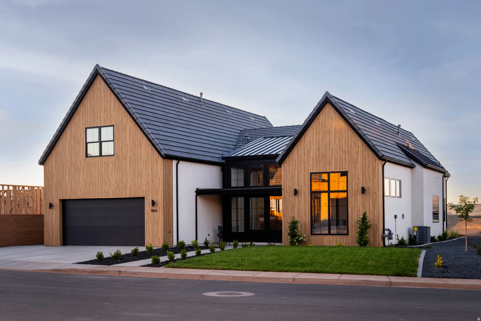 Modern farmhouse exterior with a light wood-finish facade and contrasting white stucco