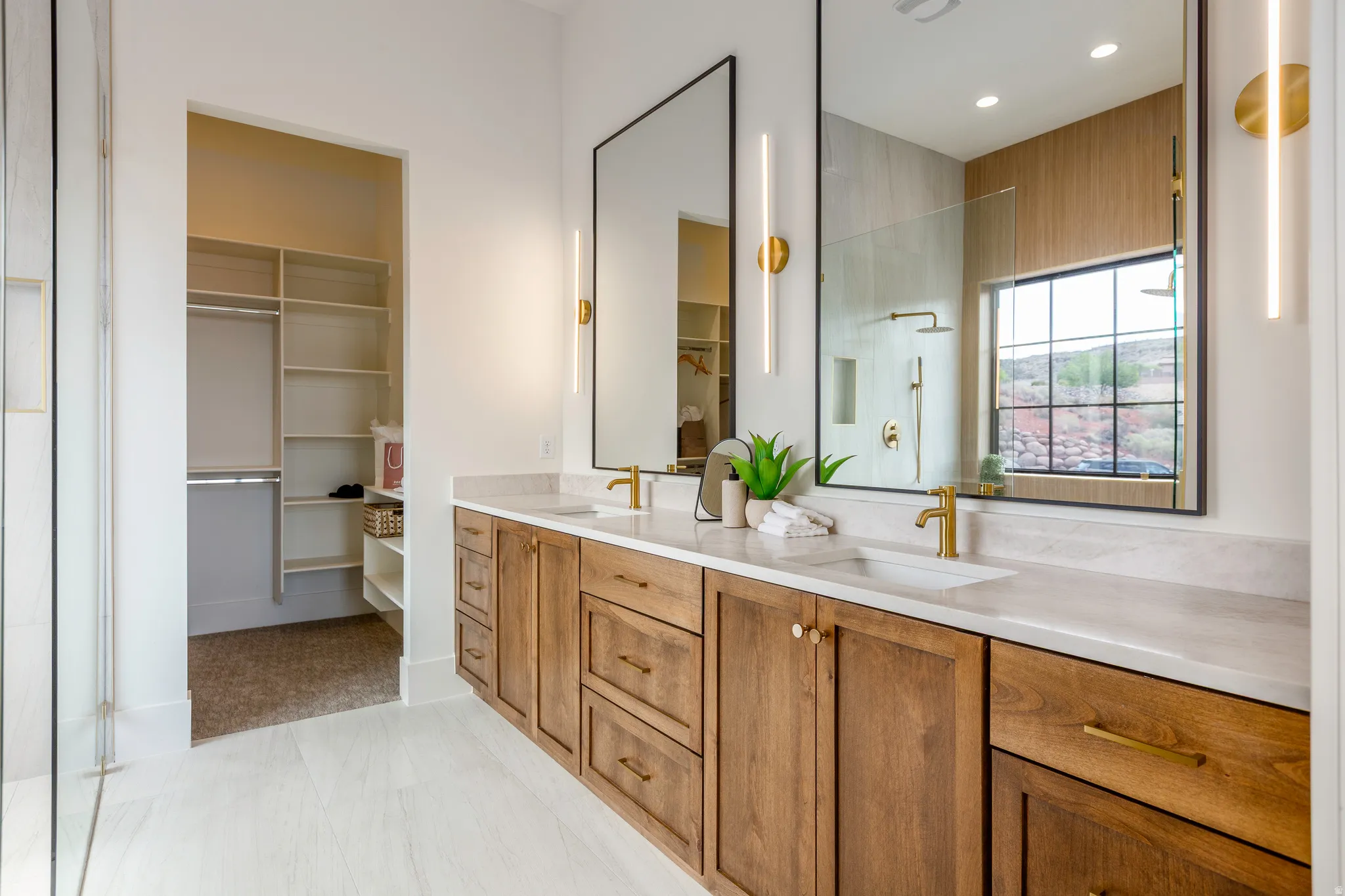 Floating dual vanity with wood-finish cabinetry, integrated sinks, and brass-finish hardware
