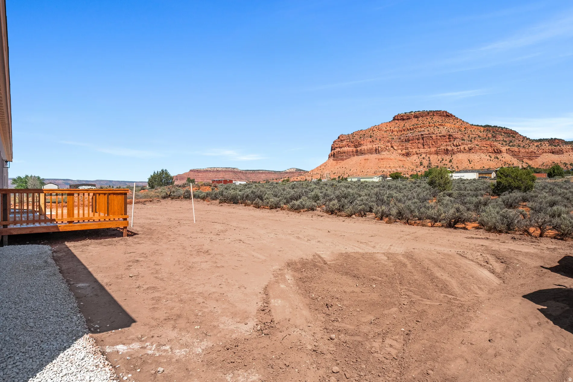 Expansive outdoor space featuring a new wood deck, gravel perimeter, and natural desert landscaping