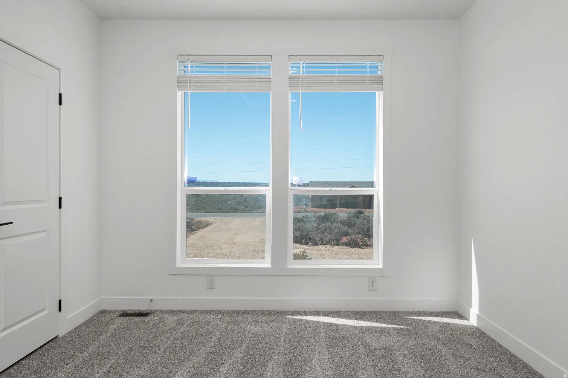 Room featuring two windows with horizontal blinds, providing natural light