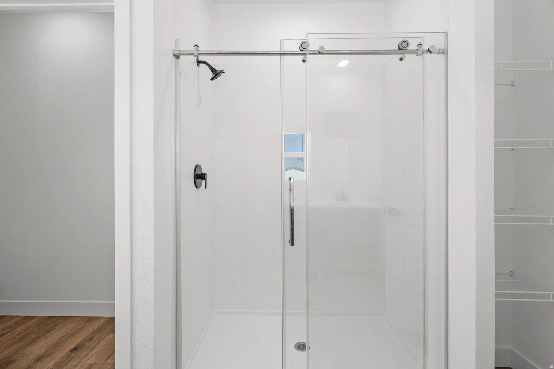 Glass-enclosed shower with a sliding barn-door style entry and matte black fixtures