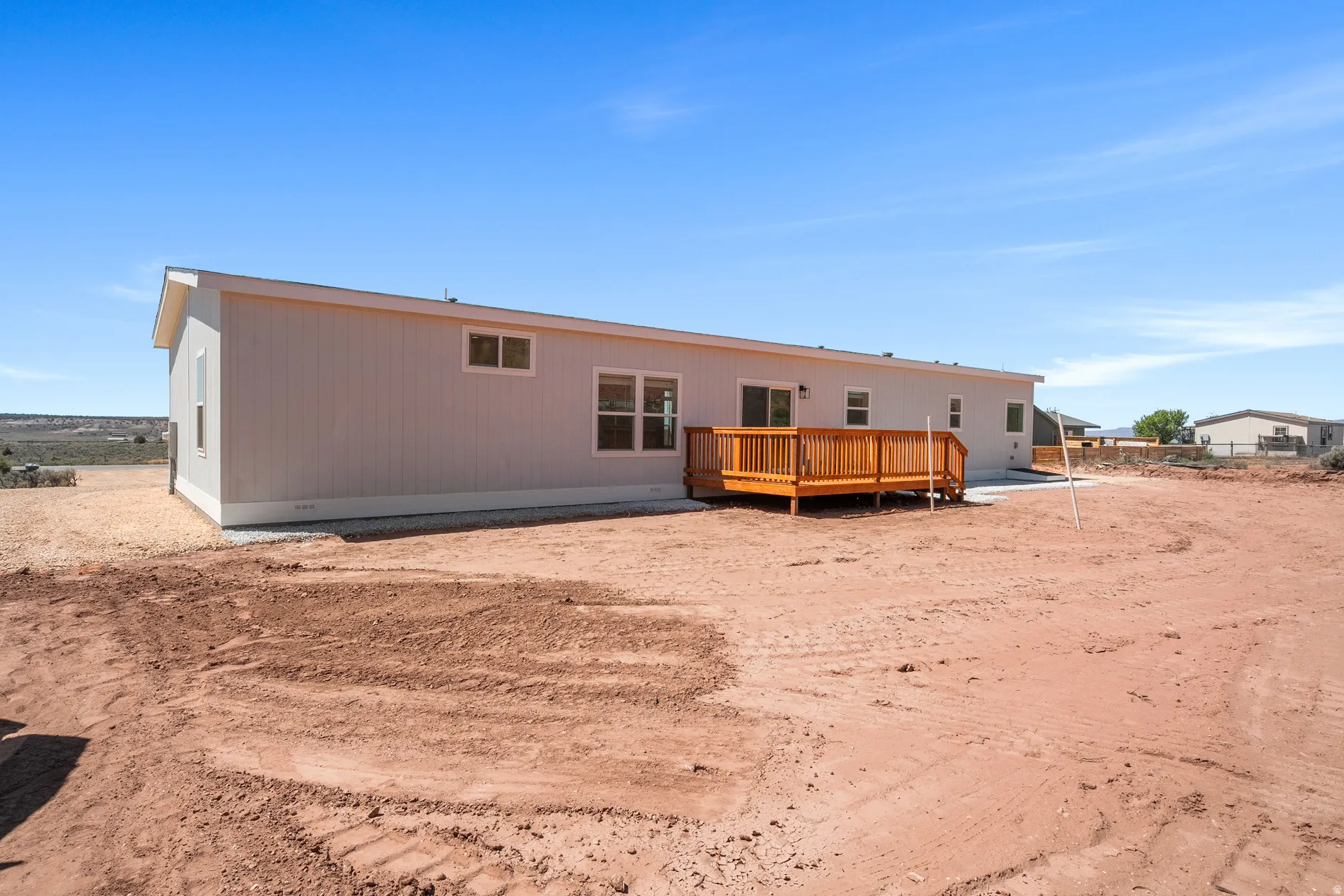 Rear exterior featuring light-colored siding and a newly constructed wood deck