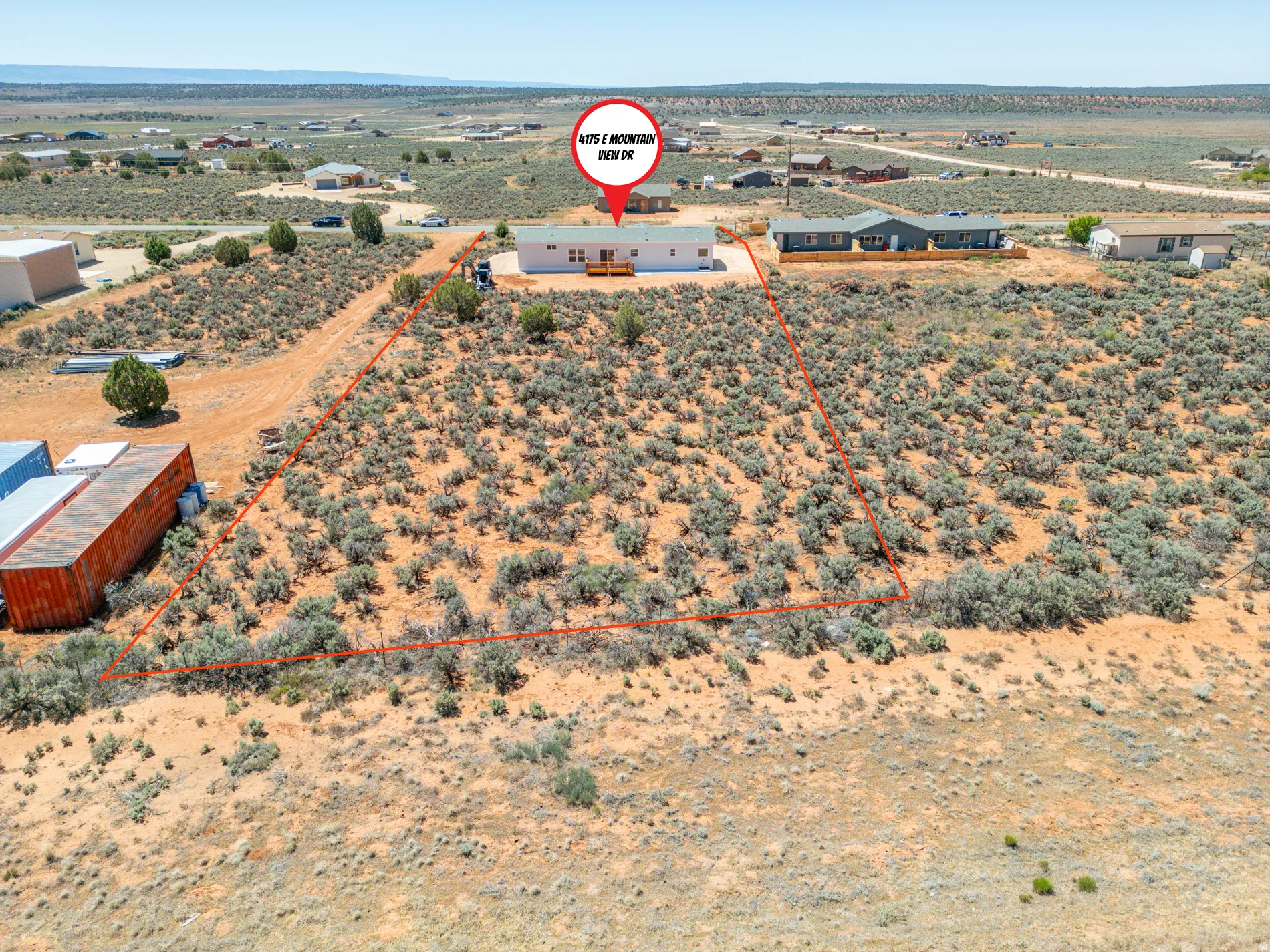 Expansive desert landscape featuring natural scrub brush and surrounding properties