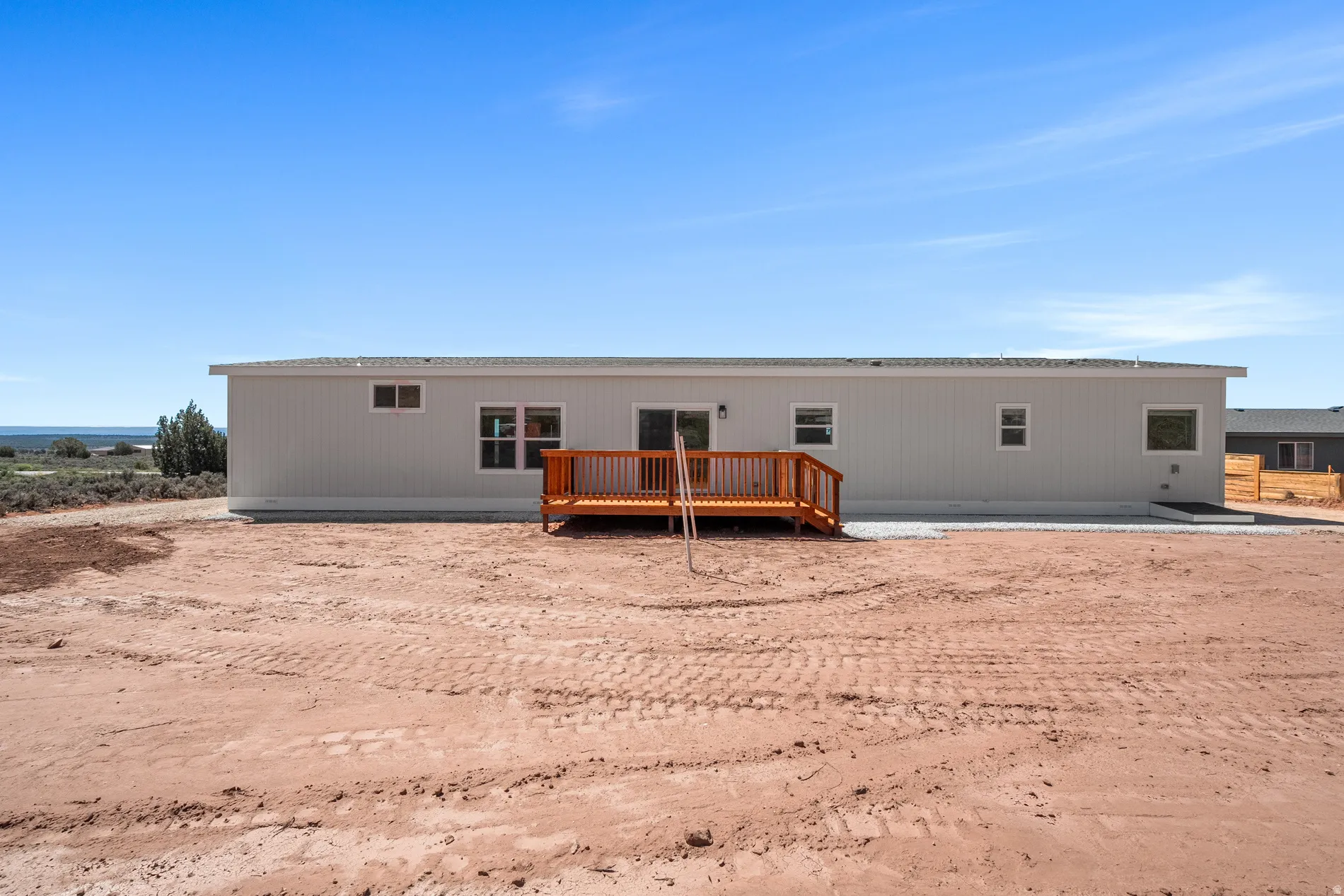 Rear exterior featuring a wood deck, multiple windows, and light gray siding