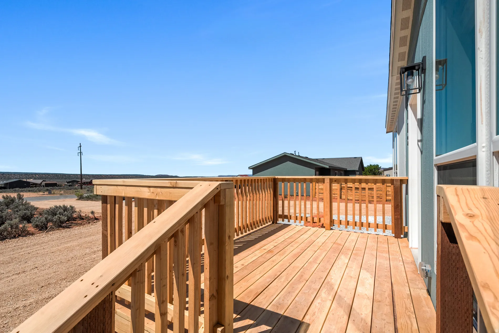 Expansive wood deck with natural wood railing and exterior wall lantern