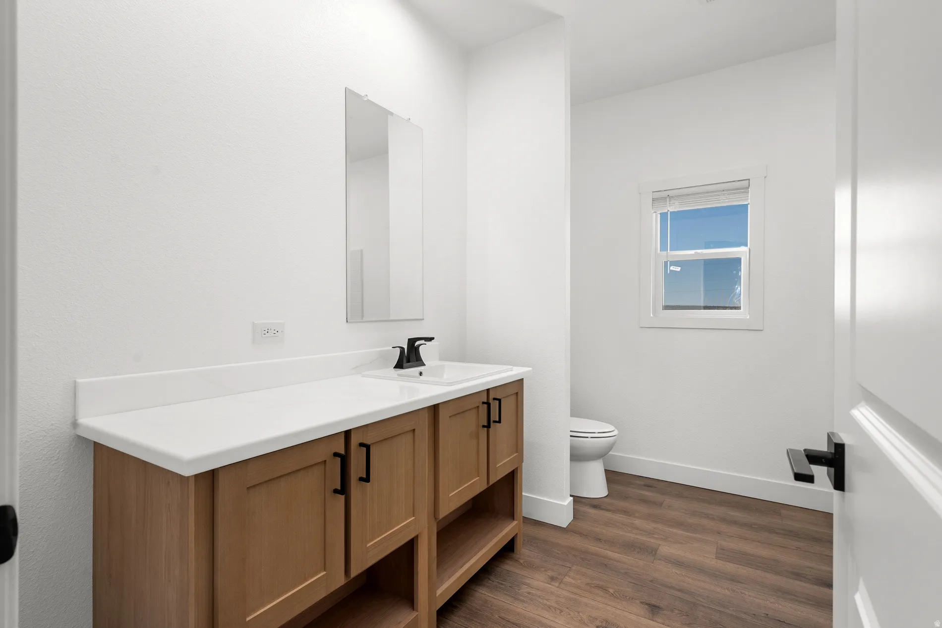 Bathroom featuring a wood-finish vanity with dual sinks and matte black fixtures