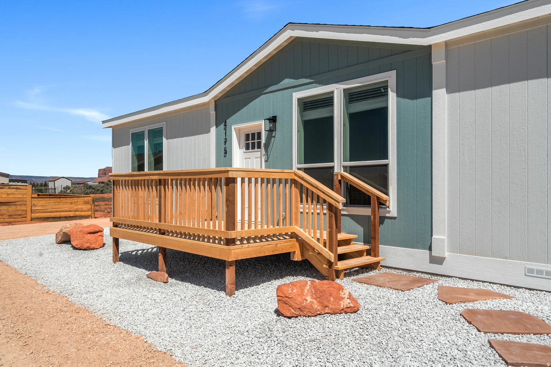 Entryway deck with wood railing and steps, complemented by a gravel ground cover