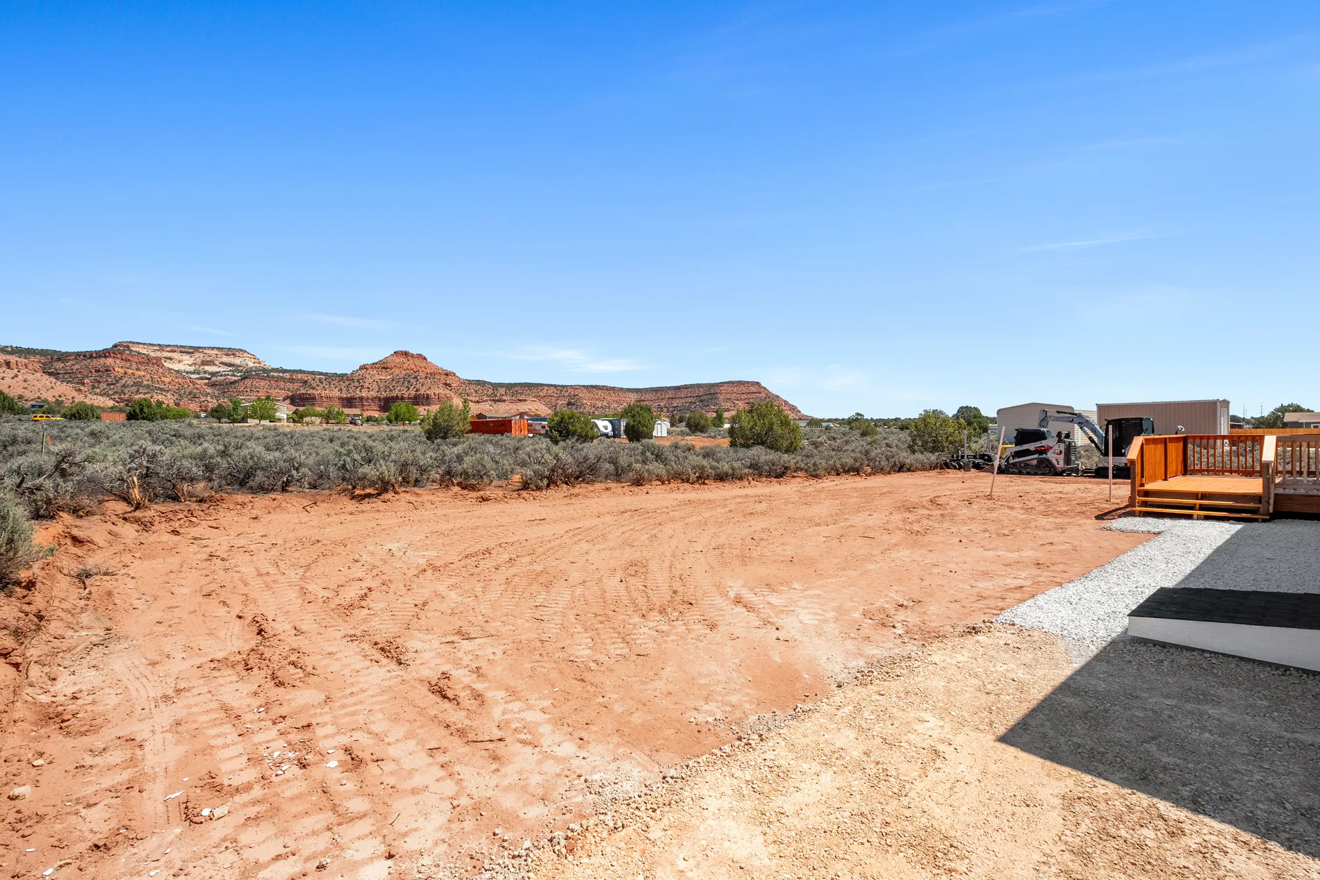 Expansive outdoor area featuring a newly constructed wood deck and gravel patio