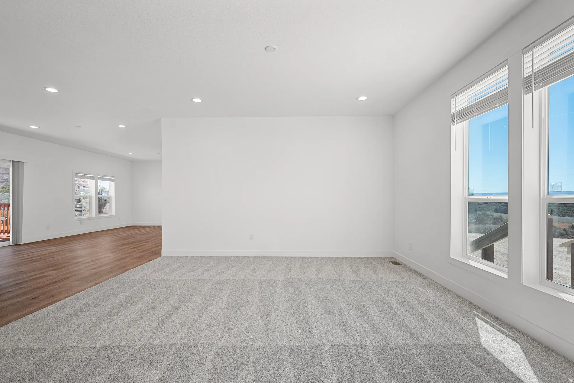Spacious interior featuring a combination of light-toned carpeting and wood-finish flooring, recessed lighting, and expansive windows