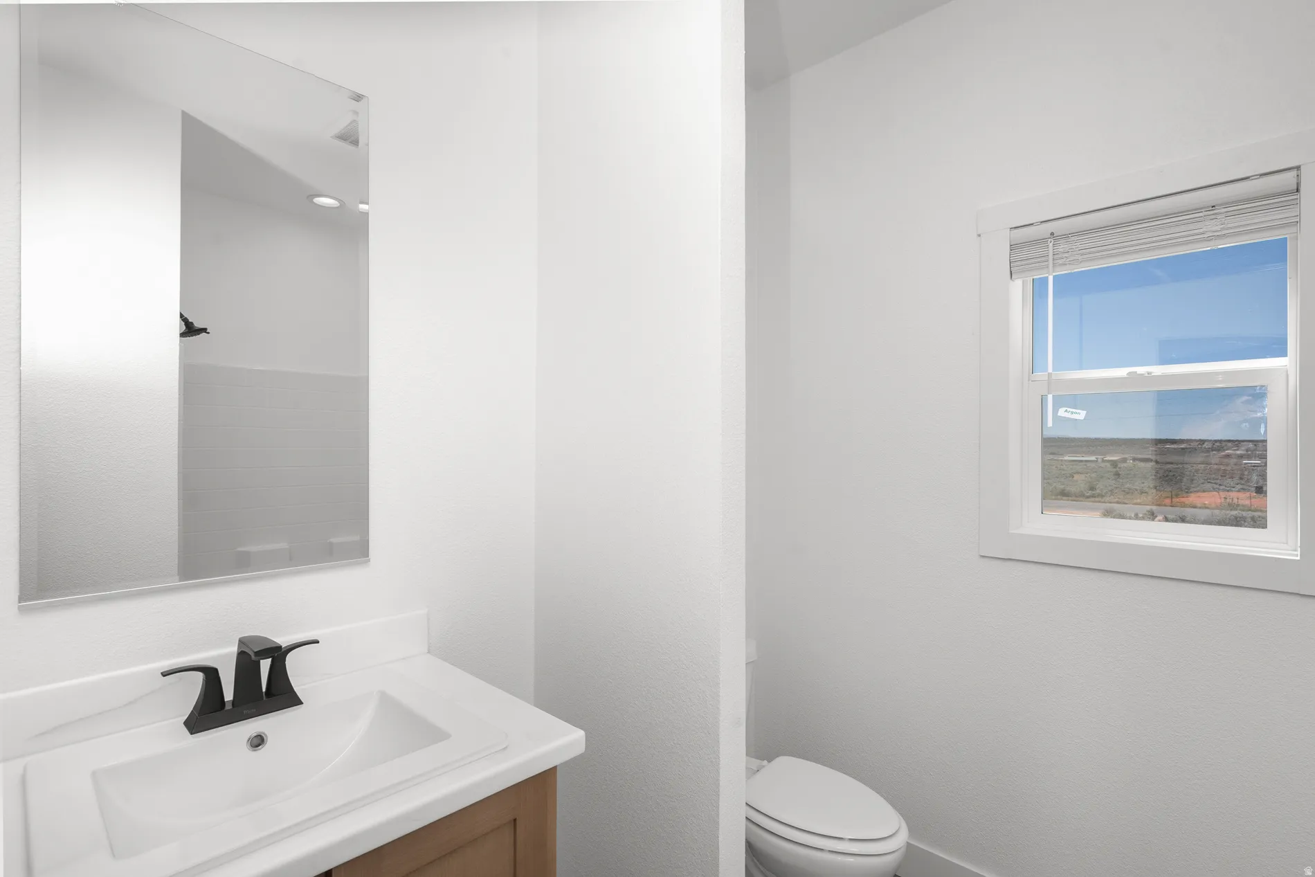 Bright bathroom featuring a contemporary vanity with an integrated sink, a dark bronze faucet, and a large wall-mounted mirror