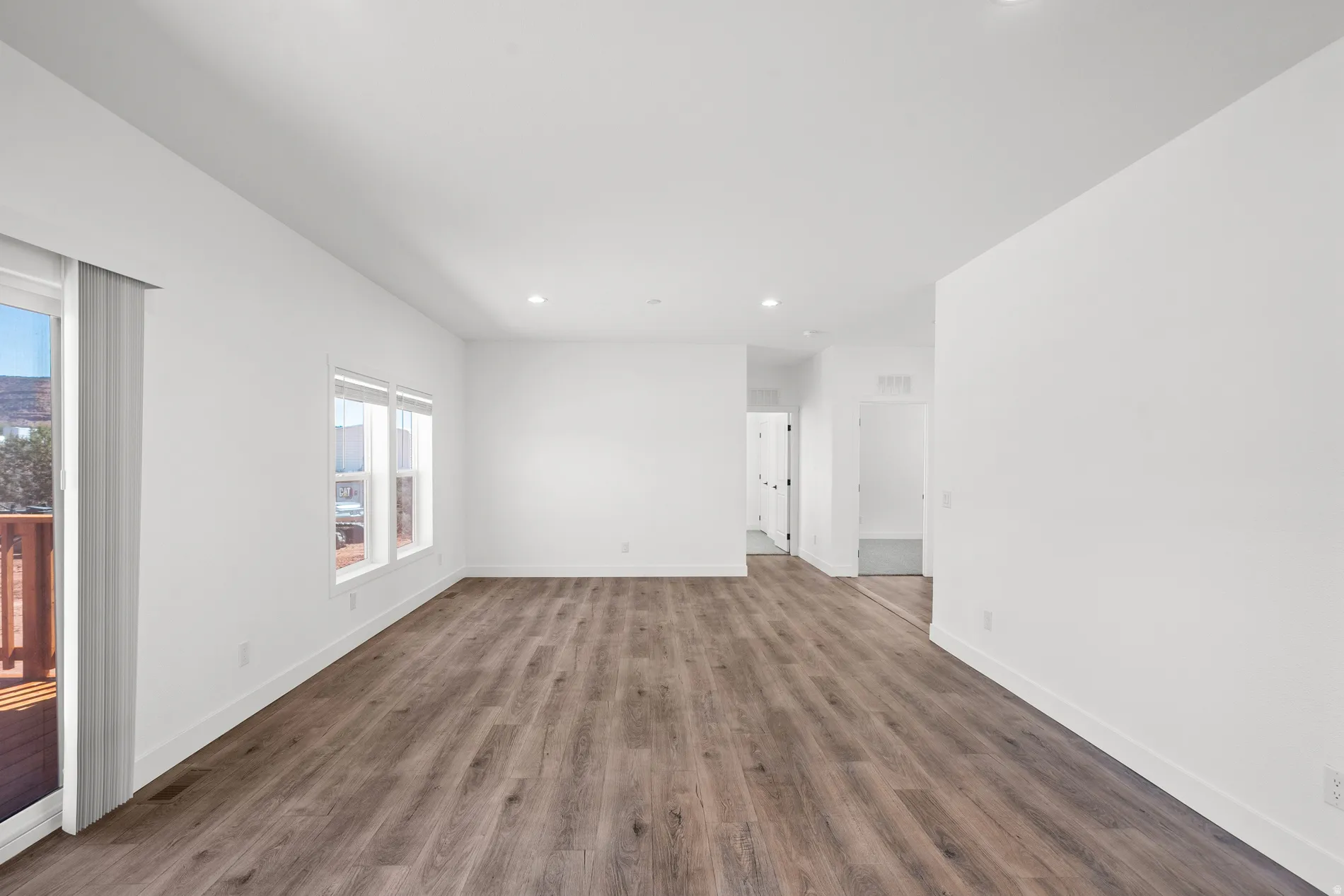 Spacious room featuring wood-finish flooring, recessed lighting, and multiple windows