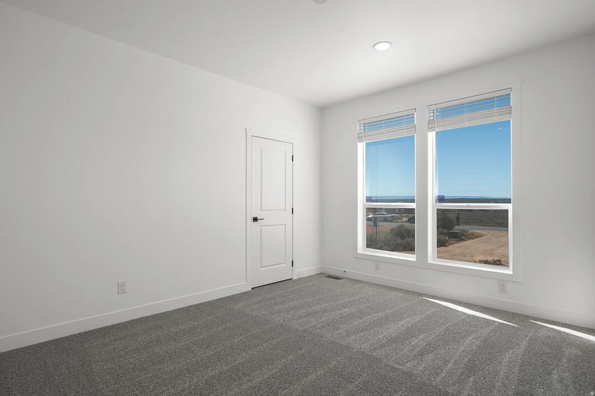 Interior room featuring a neutral color palette, grey patterned carpeting, and white baseboards