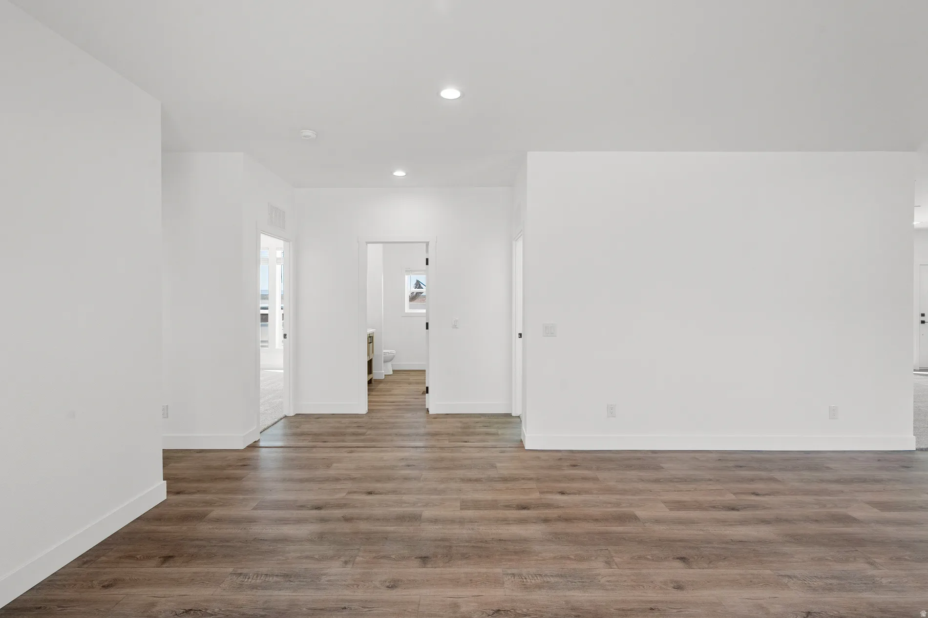 Open concept interior featuring wood-finish flooring, recessed lighting, and white walls
