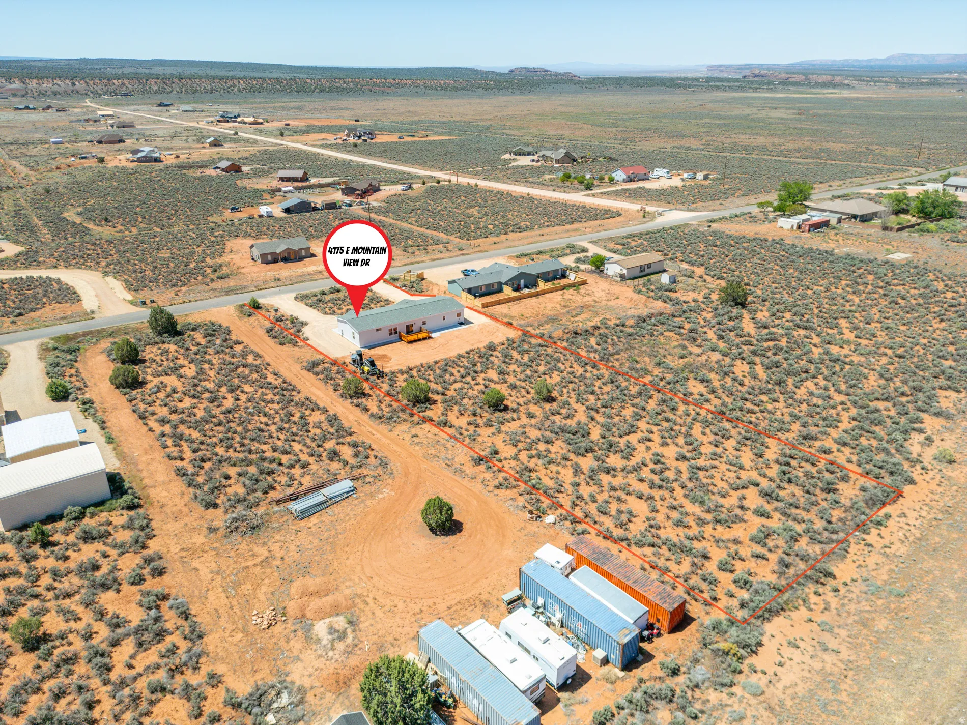 Expansive high desert lot featuring a single-story residence with a light-colored exterior and a contrasting roof